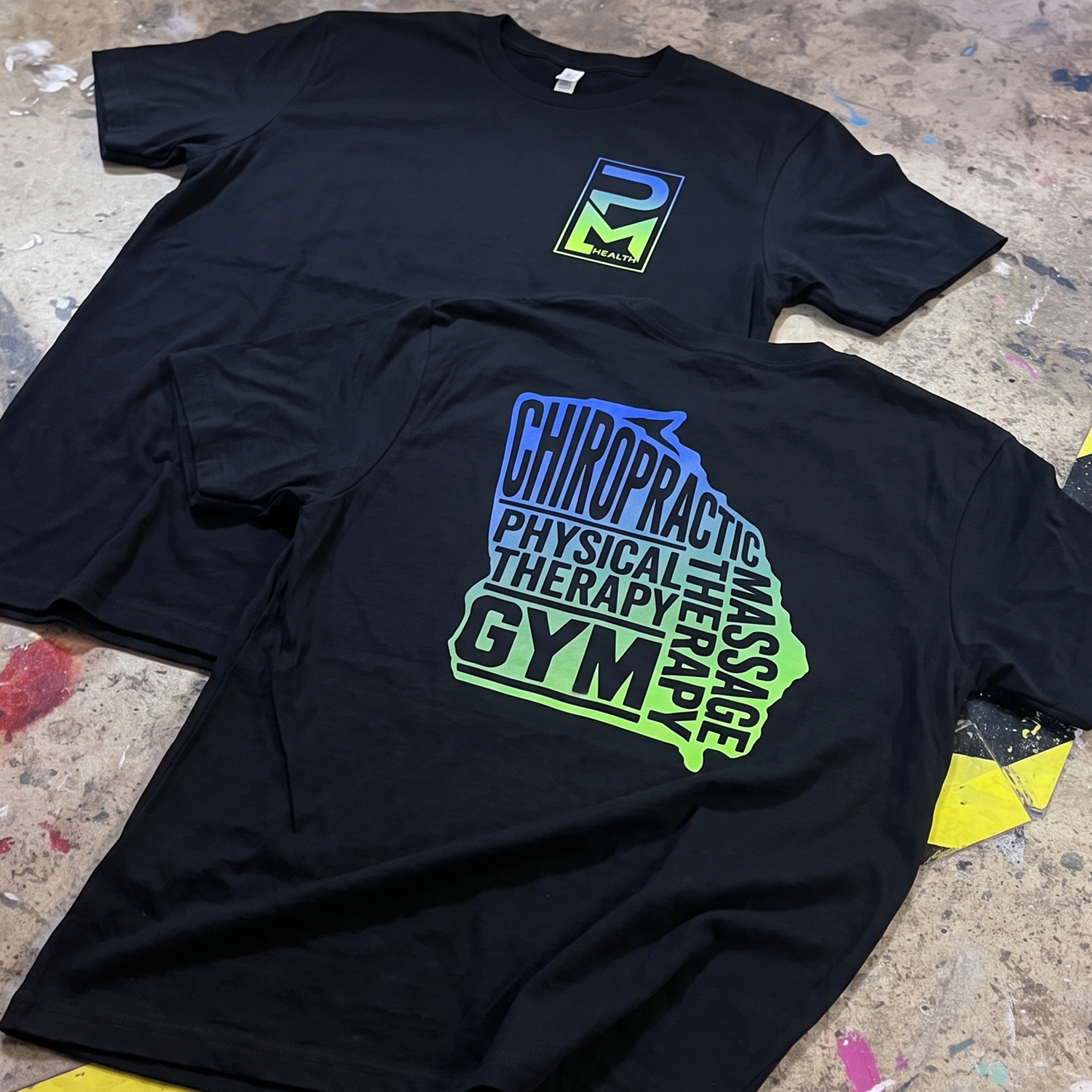 Black T-shirts with gradient PM Health chest logos and large stacked back graphics.