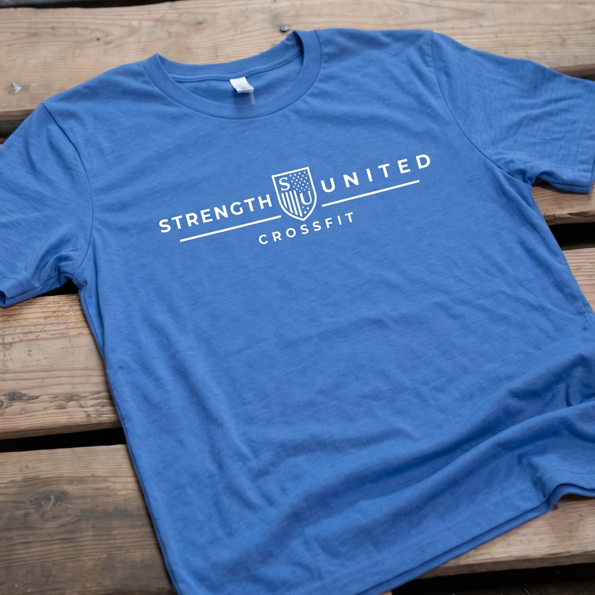 Blue T-shirt with a white Strength United CrossFit crest wordmark.