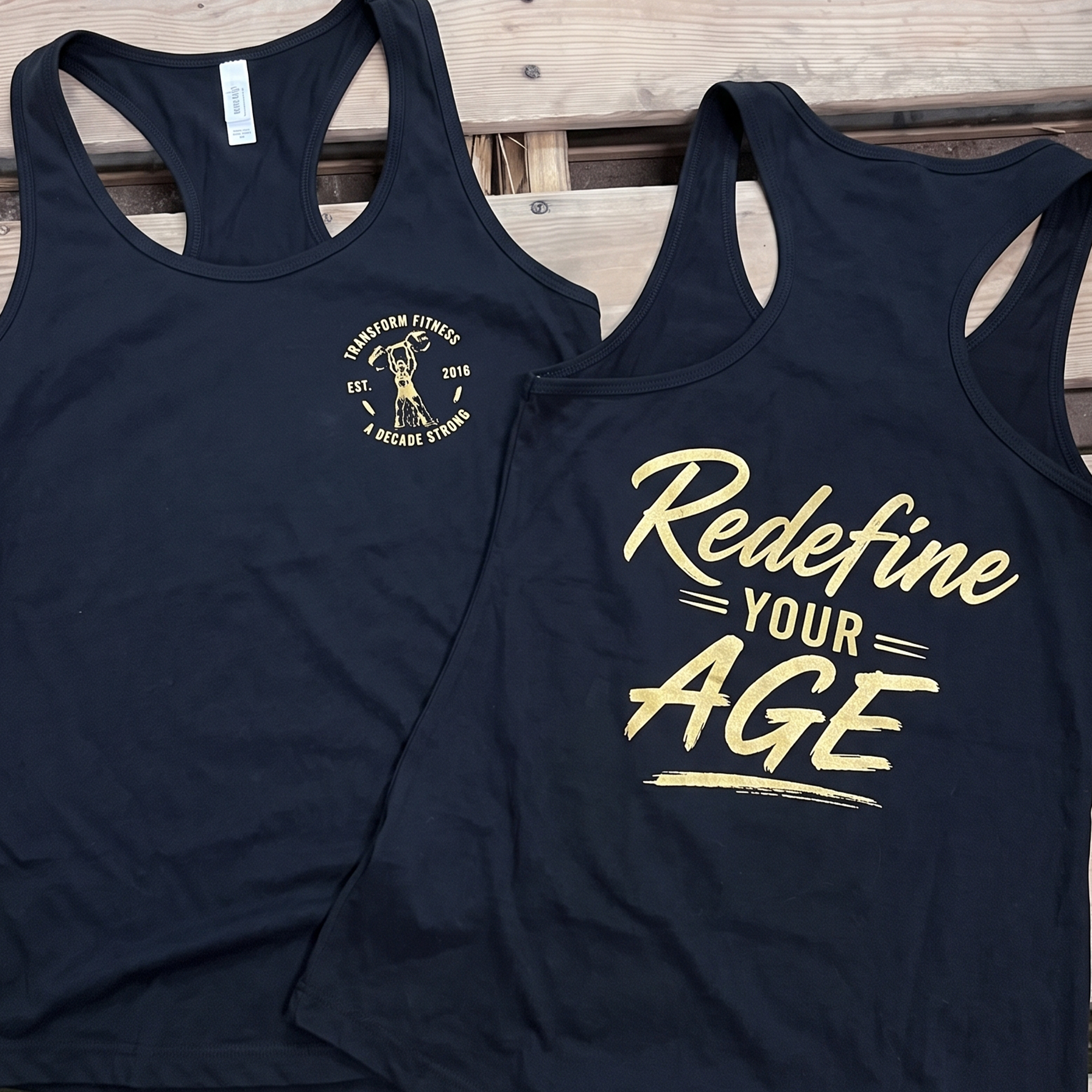 Black racerback tanks with gold anniversary crest and Redefine Your Age print