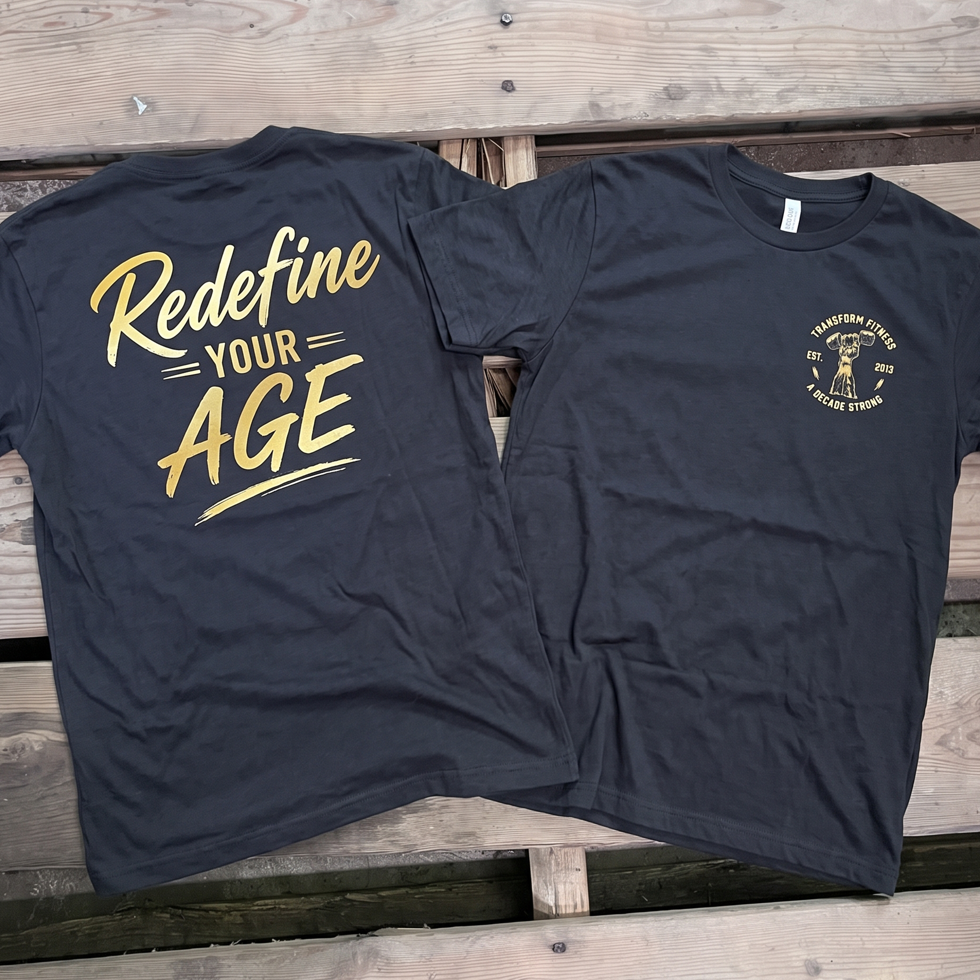 Black T-shirts with gold anniversary crest and large Redefine Your Age back print