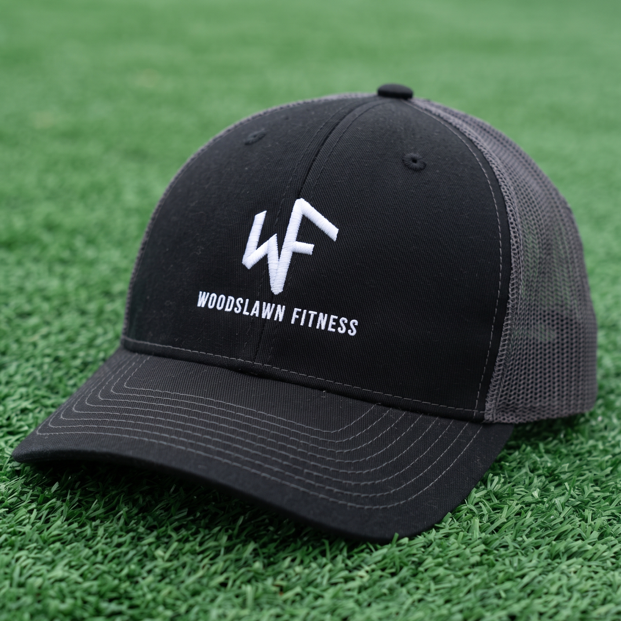 Black and gray mesh cap with white embroidered Woodslawn Fitness logo.
